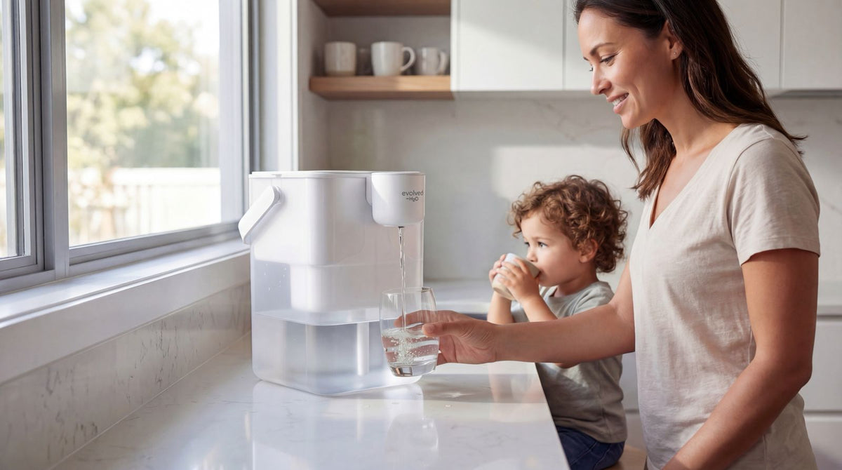Mother and child in the kitchen, pouring filtered water from the HydroX electric water filter