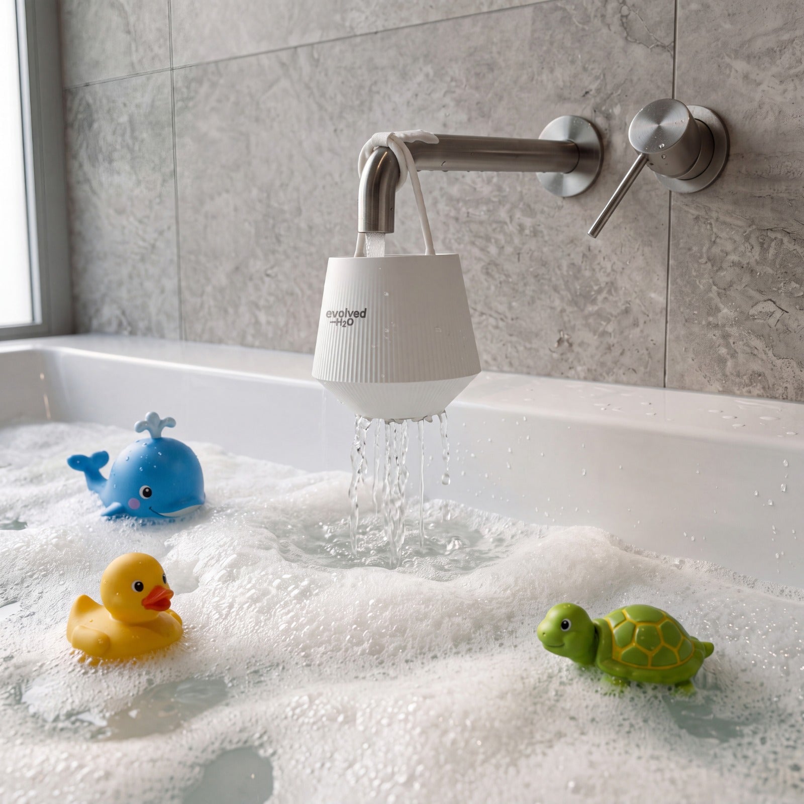 Evolved H2O bath filter hanging from a bath tap with water flowing into a bubble bath with children’s bath toys