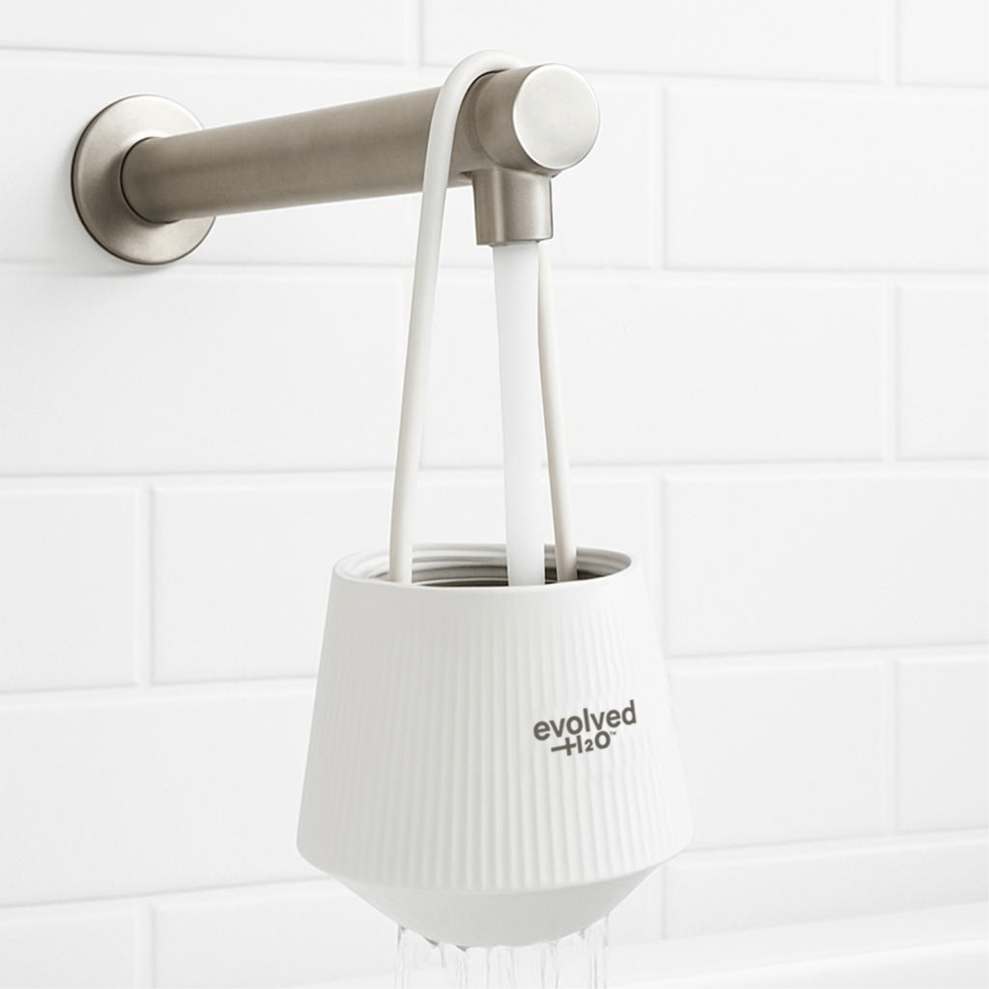 Evolved H2O bath filter hanging from a bath tap with water running through it