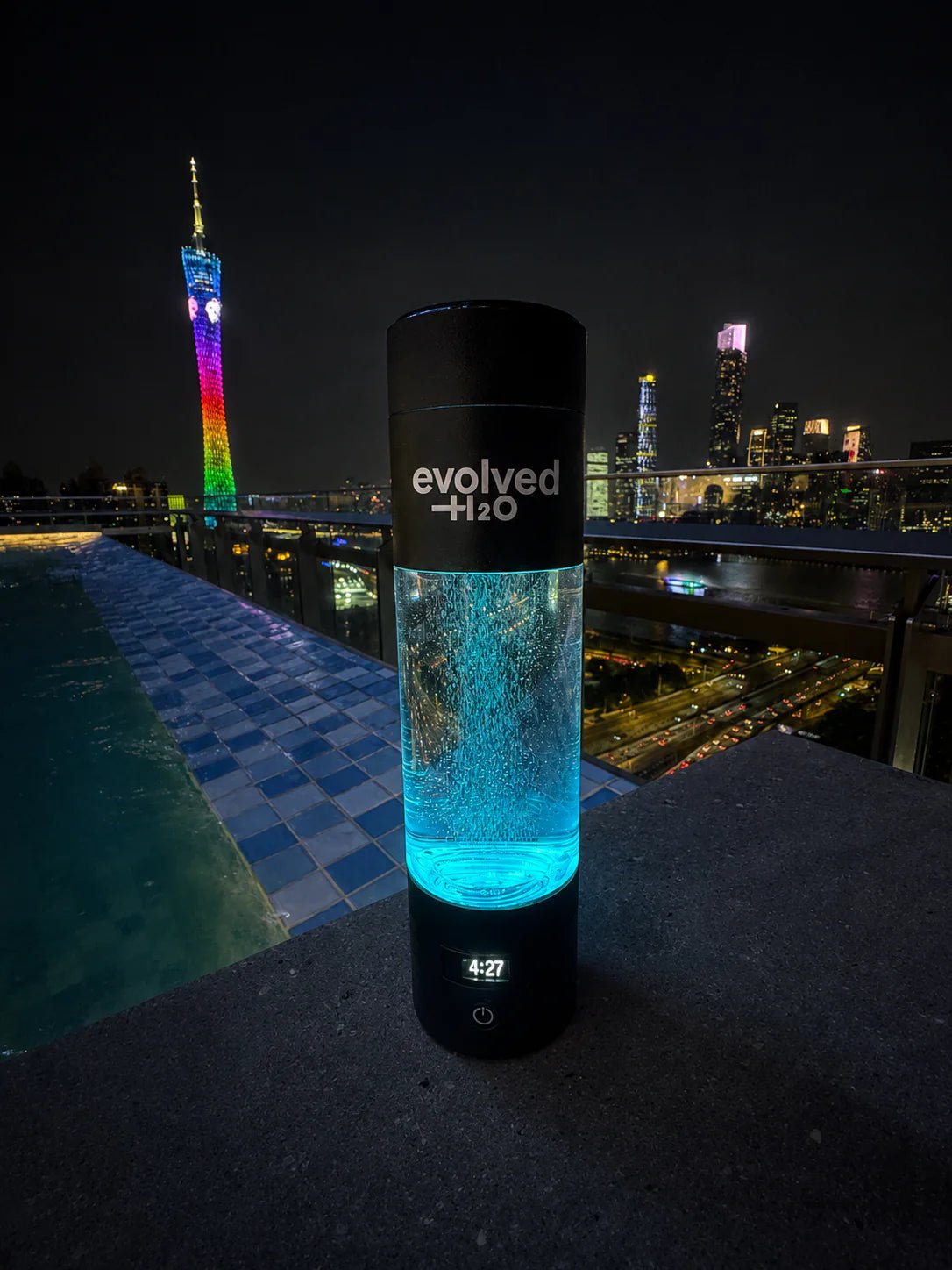 Black Evolved H2O Hydrogen Pro Bottle glowing blue against a city skyline at night