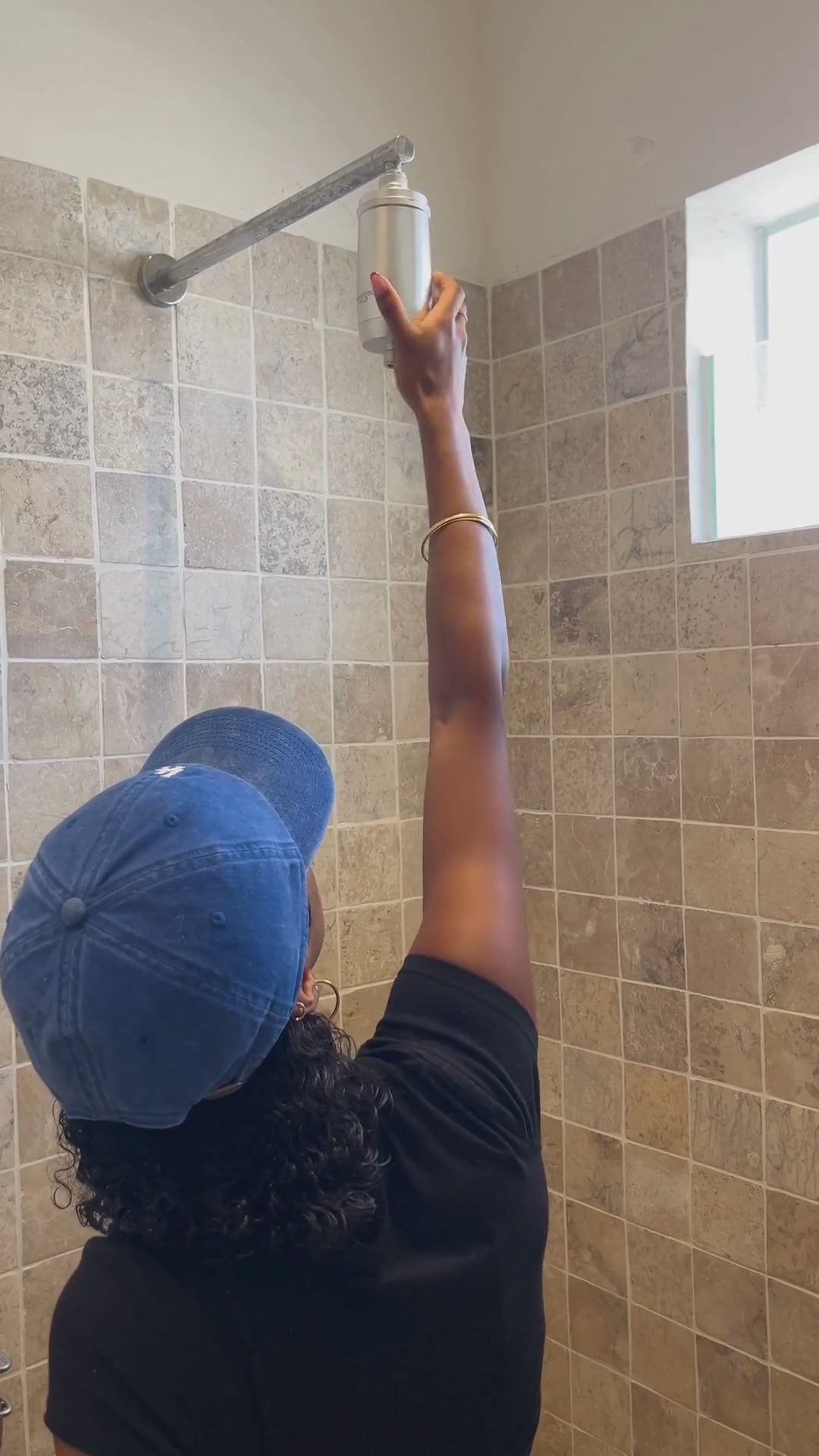 Person installing an Evolved H2O shower filter on a wall-mounted shower arm.