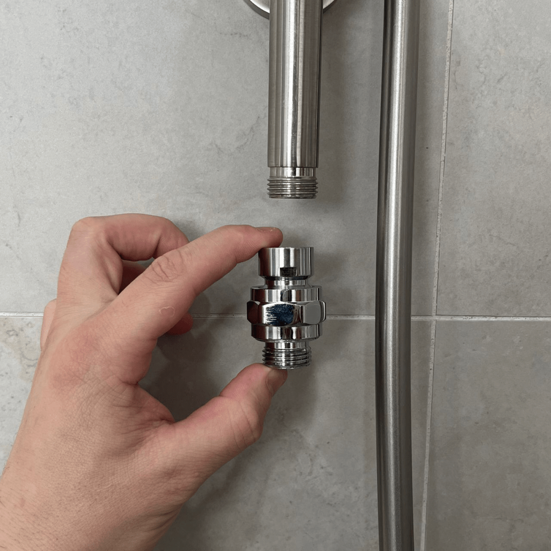 Hand positioning the swivel ball adapter beneath a compatible shower arm for Evolved H2O shower filter installation